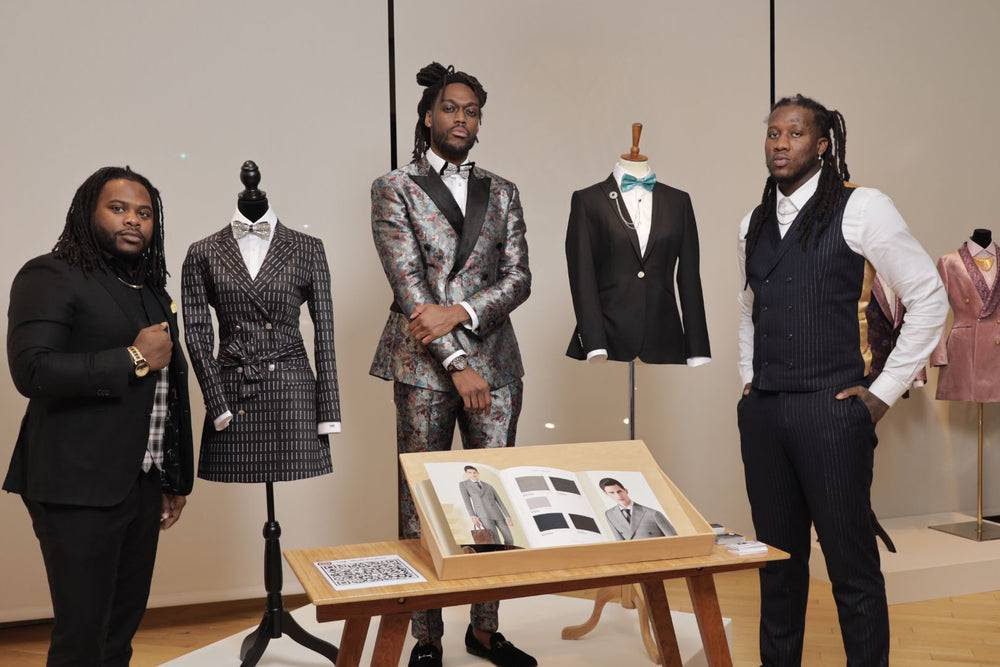 Self-Made Couture presenters beside tailored garments at a community event