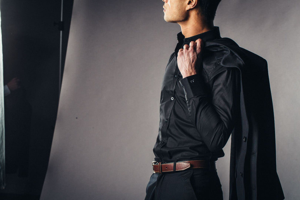 Person wearing a fitted black shirt and dark trousers