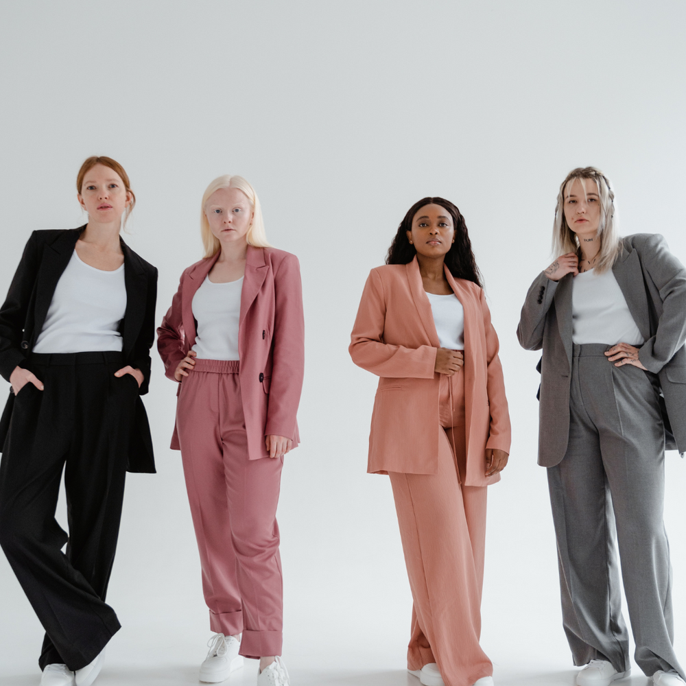 Four people wearing suits in black, pink, coral and gray